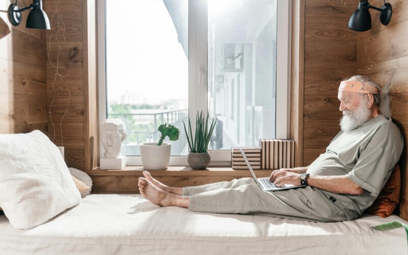 SENIOR WITH DISABILITY ON LAPTOP IN BED