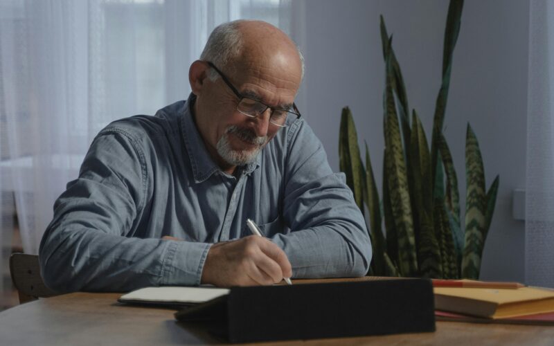 SENIOR GENT WRITING AT DESK
