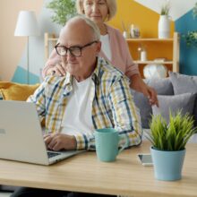 SENIOR COUPLE WORKING AT HOME ON LAPTOP