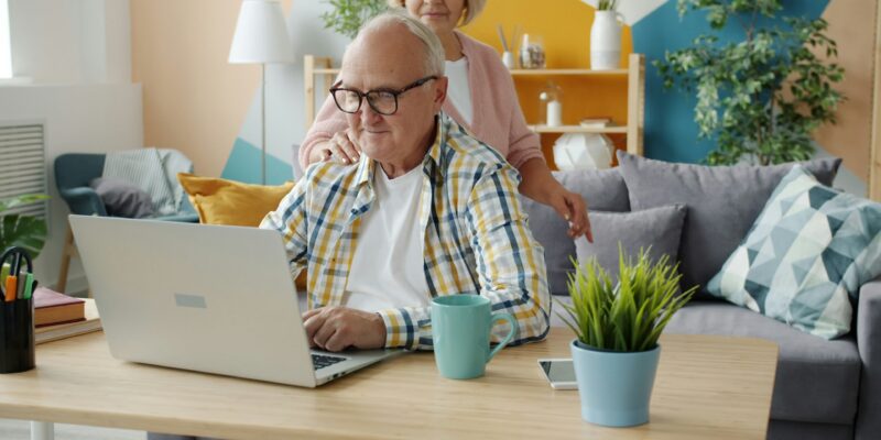 SENIOR COUPLE WORKING AT HOME ON LAPTOP