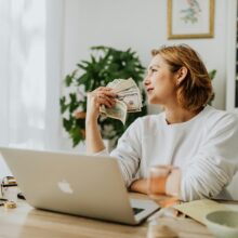 Female senior at desk hold dollar bills